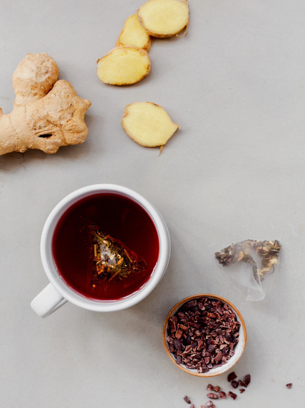 Mission Energise tea brewing with cocoa nibs, ginger and a plastic free teabag next to it