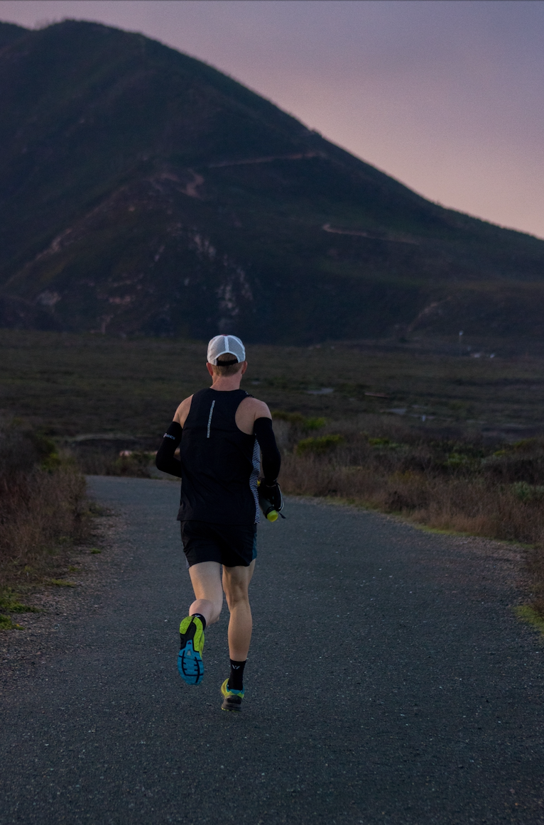 man running towards mountain. Sunset sky